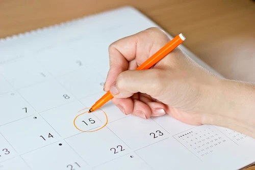 Woman circling the 15th day of the month on a calendar