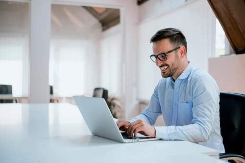  Image of a man smiling while working on his laptop.