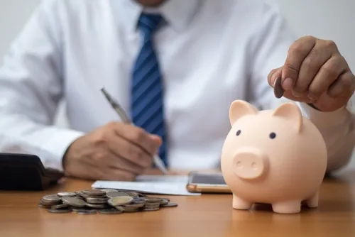 Man dropping a coin into a piggy bank