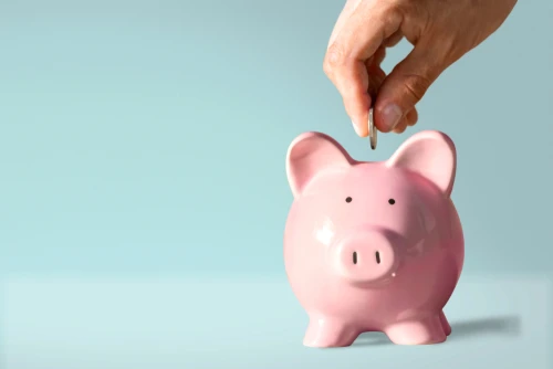 Man placing a coin into a piggy bank