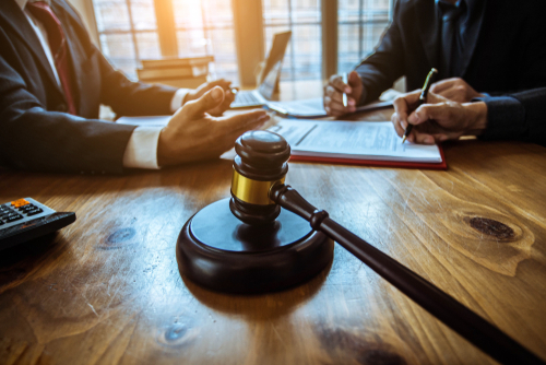 Two people negotiating an agreement with a gavel in the background