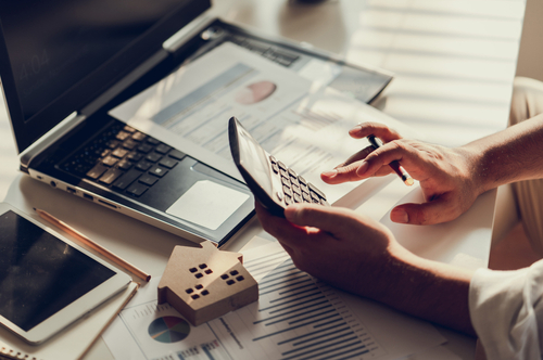 Man typing on calculator in front of computer