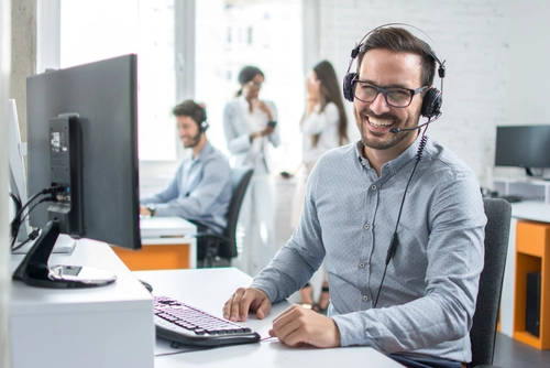 Man sitting in front of a computer wearing a headset.